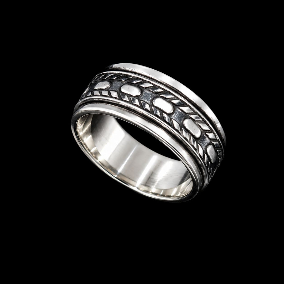 A silver band ring with enamel work design on a plain background