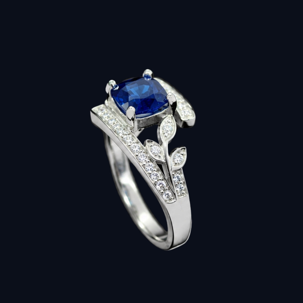 A silver-toned ring with a blue CZ stone at its center, surrounded by a delicate floral design.