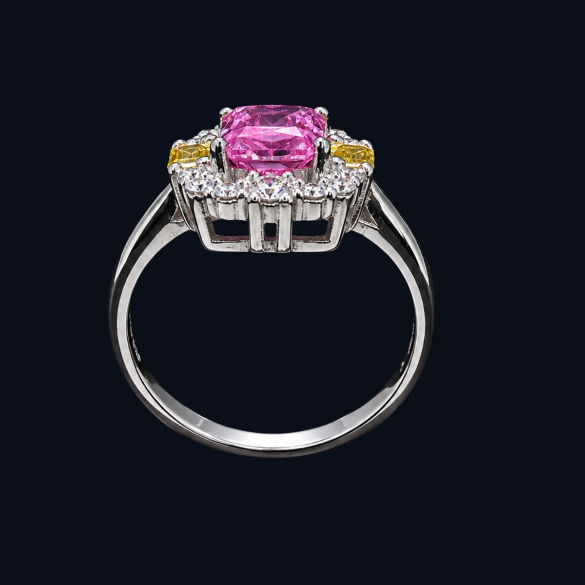 A silver ring with a pink CZ stone and clear CZ accents, set against a dark background.