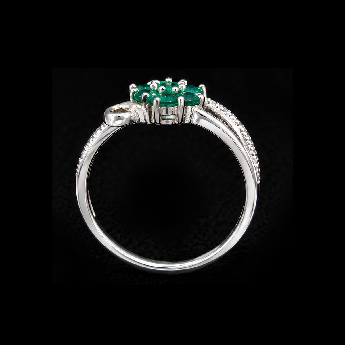 A silver ring with an emerald stone, set in a floral design.