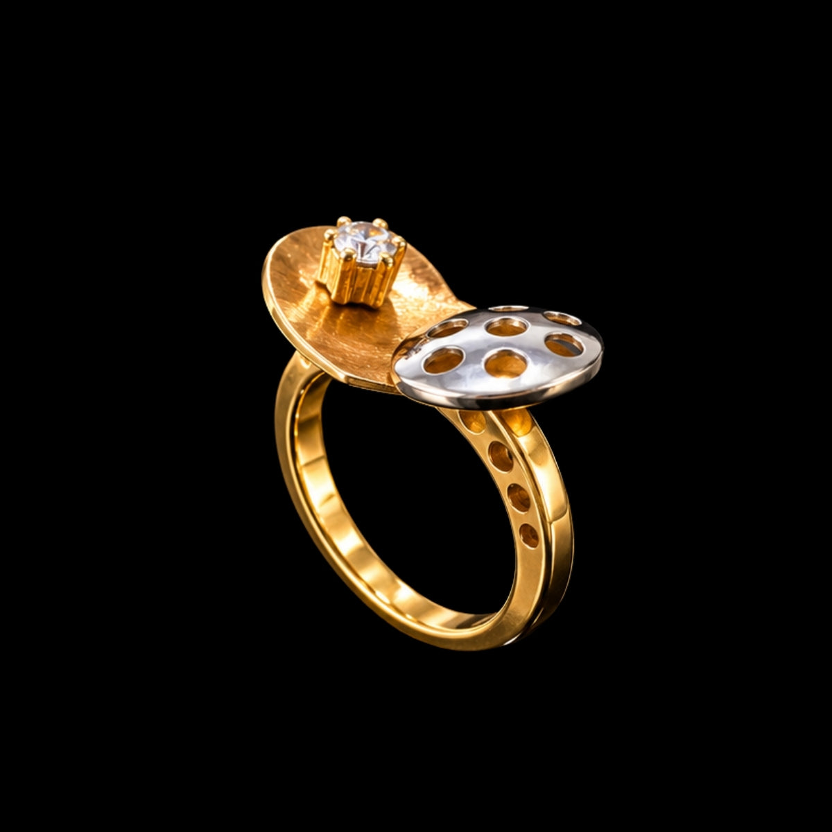 A gold and silver ring with a CZ stone on a black background.