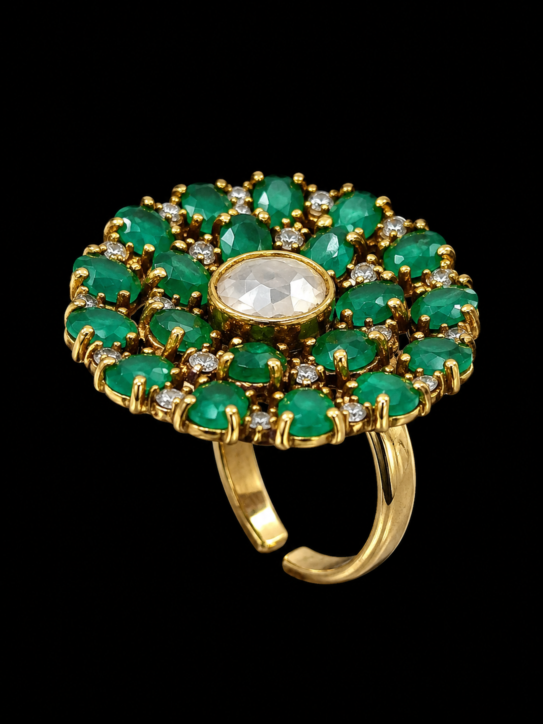 A gold-tone ring with a central white gemstone surrounded by a halo of green gemstones.