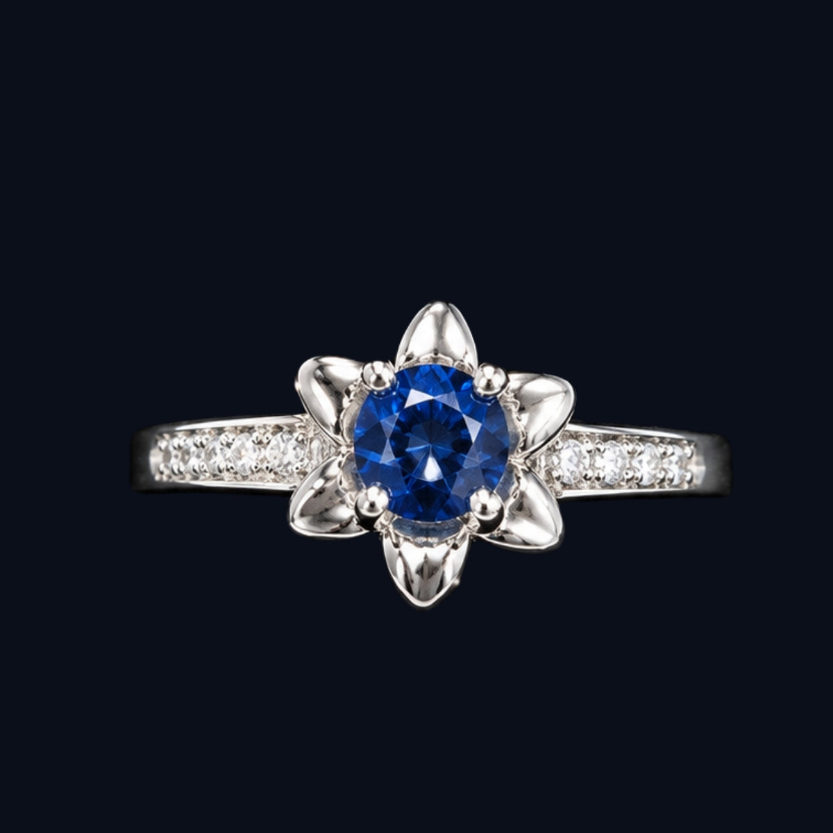 A silver ring with a blue gemstone and CZ stones on a black background.