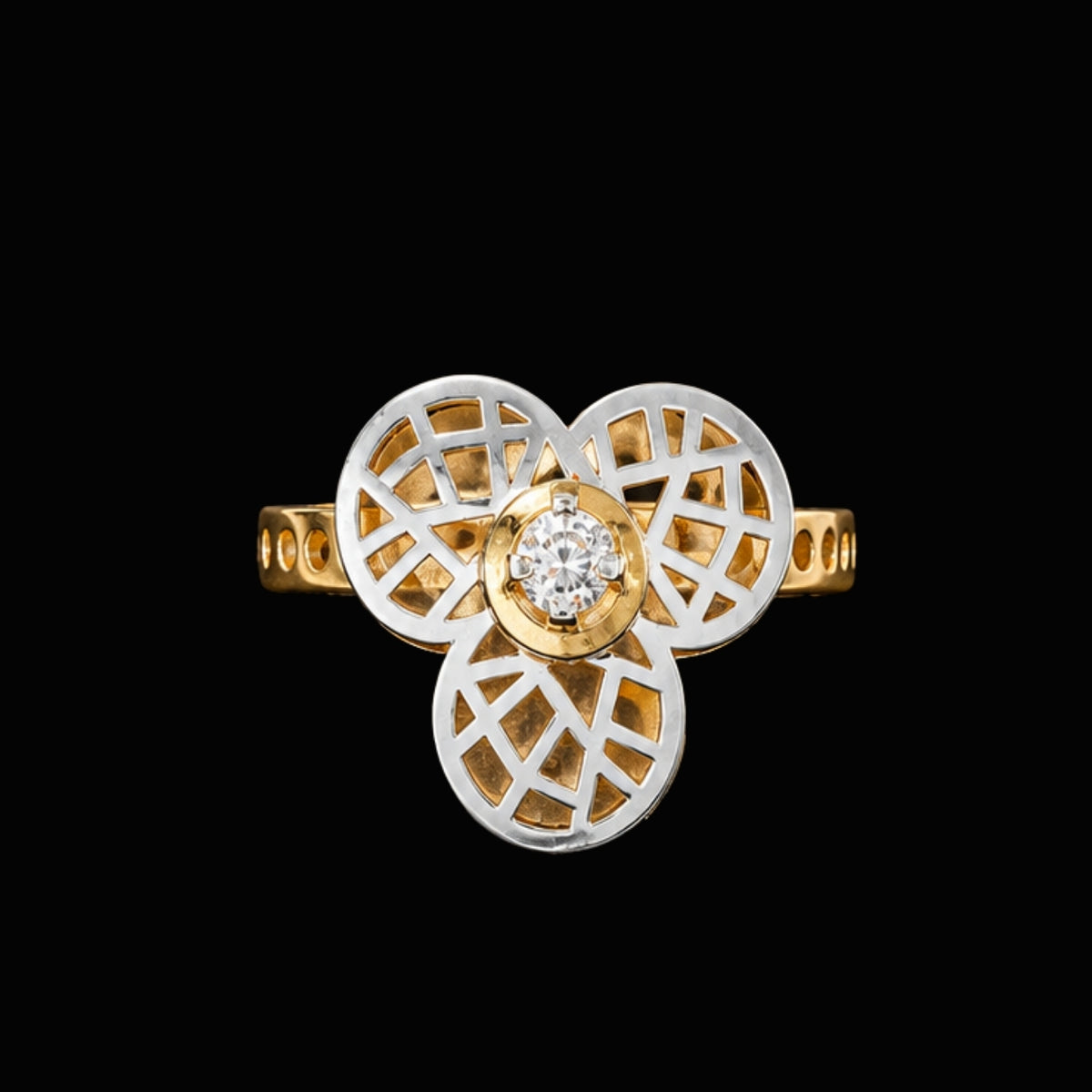 A gold and silver tone ring with a round-cut CZ stone at its center, surrounded by intricate cut-out details.