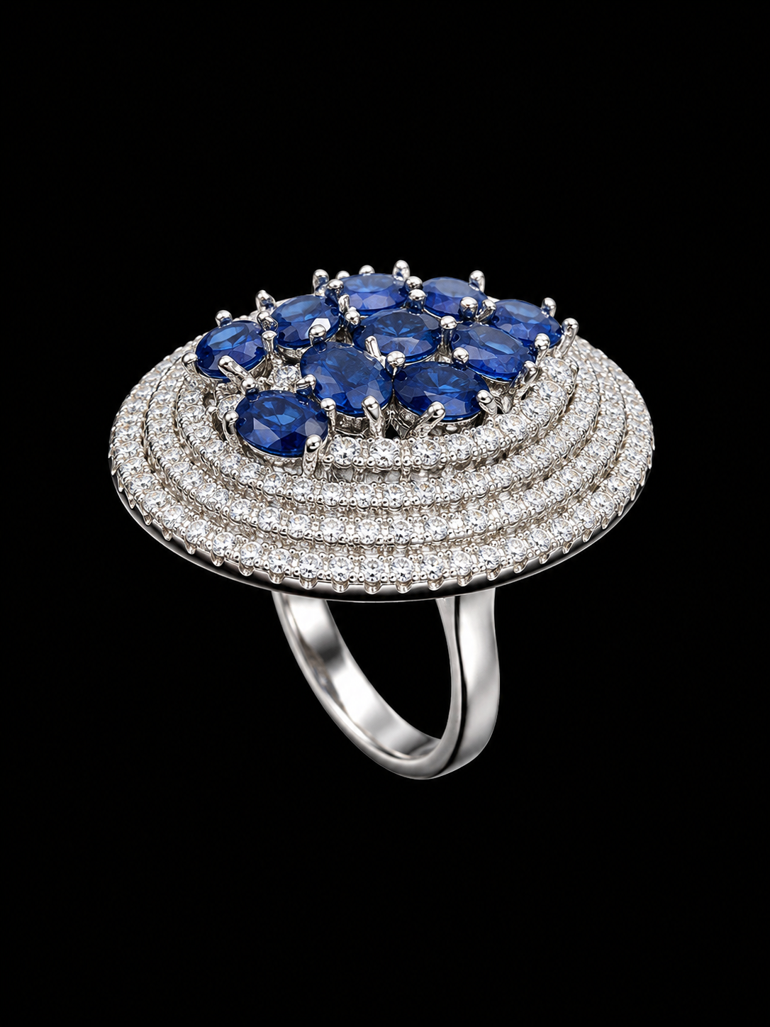 A silver ring with a blue CZ stone at its center, surrounded by a halo of smaller stones.