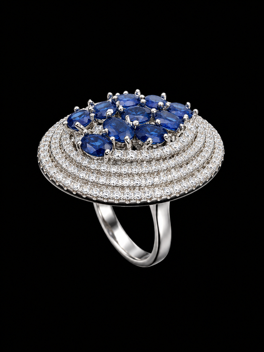 A silver ring with a blue CZ stone at its center, surrounded by a halo of smaller stones.