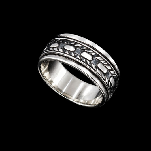 A silver band ring with enamel work design on a plain background