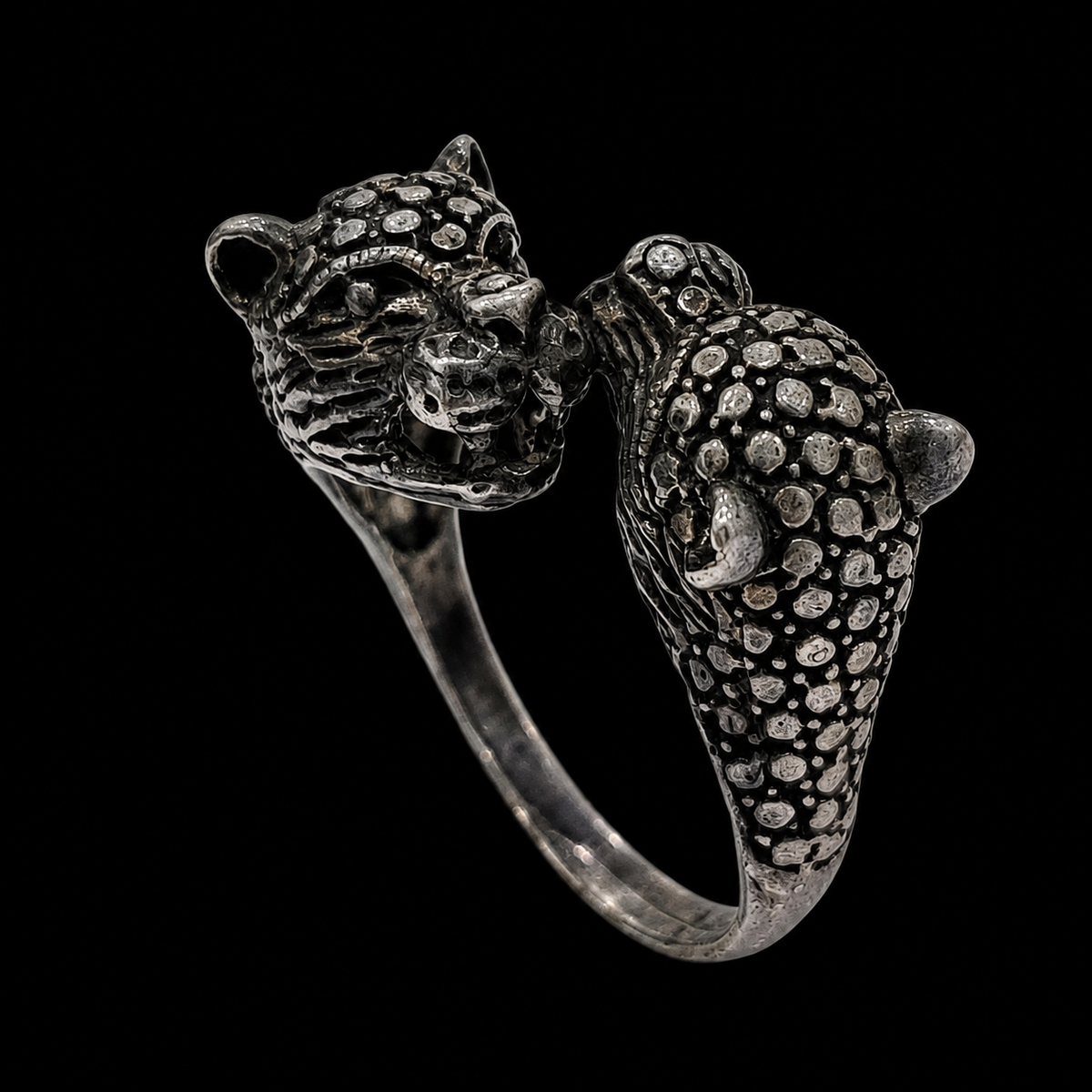 A silver ring featuring two leopard heads facing each other, with CZ stones and a textured finish.