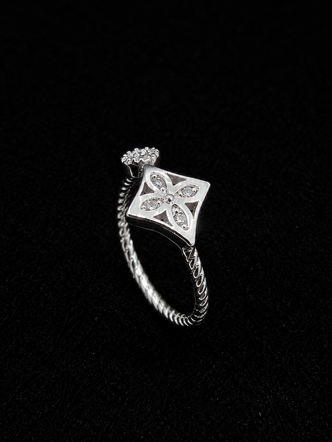 A silver ring with a square design and clear cubic zirconia stones.