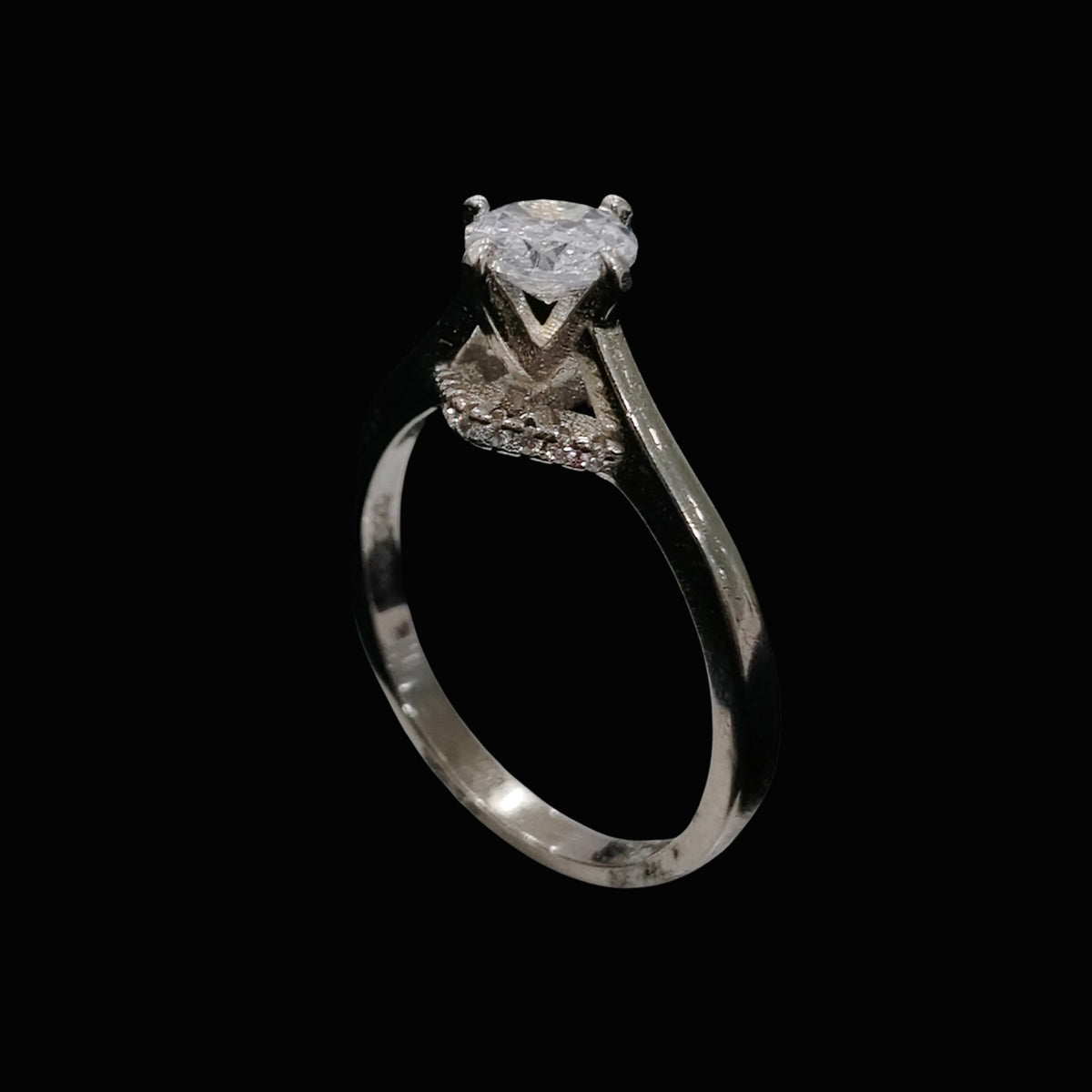 A silver ring with a large clear cubic zirconia stone on a black background.