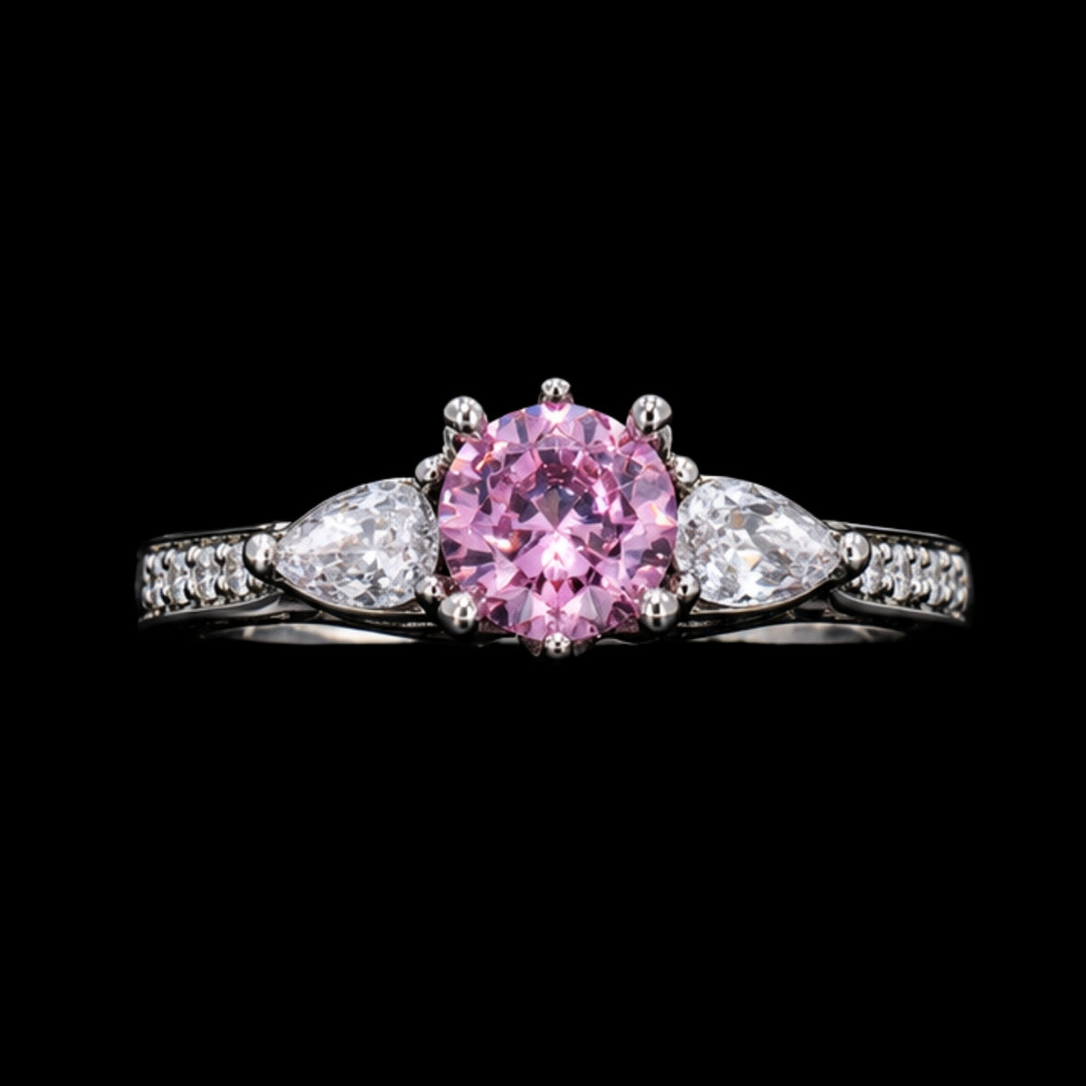 A silver ring with a pink CZ stone in the center, flanked by two white CZ stones on either side, set on a black background.