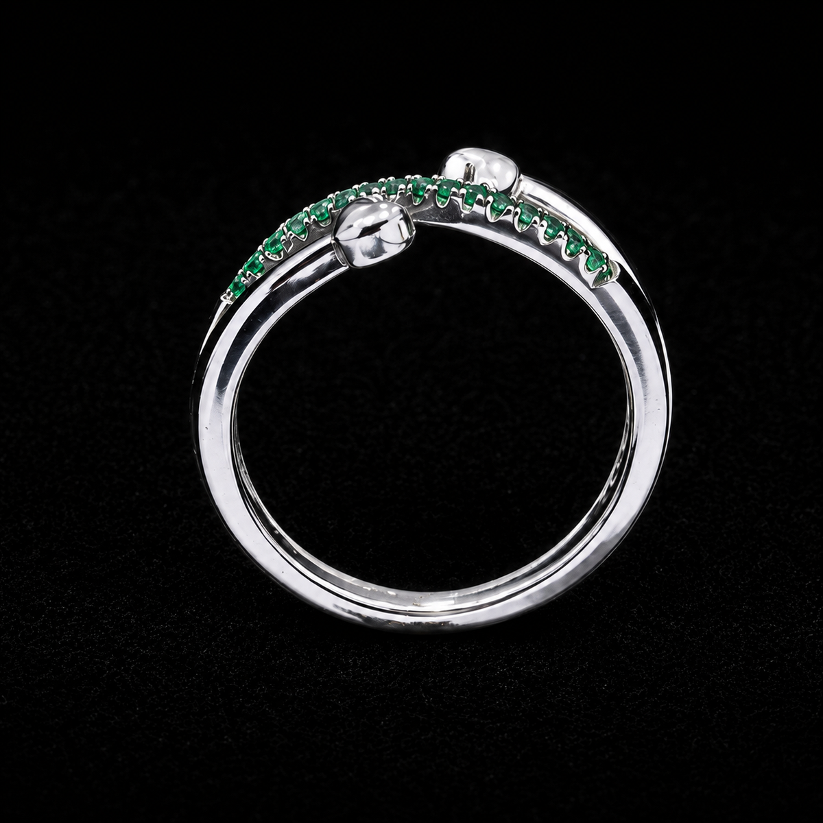 A silver ring with a row of green CZ stones along the top, set against a dark background.
