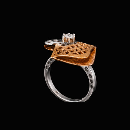A gold-tone ring with a silver-tone band and a clear CZ stone, featuring a geometric design.
