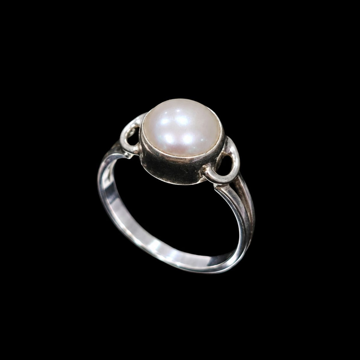 A silver ring with a single pearl in the center, set on a plain background.