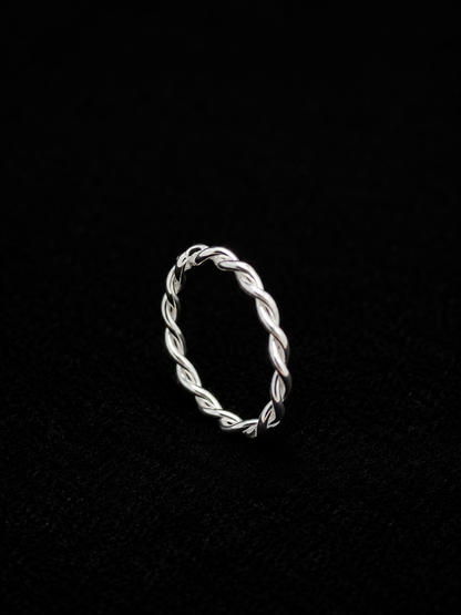 A silver ring with a twisted design on a plain background