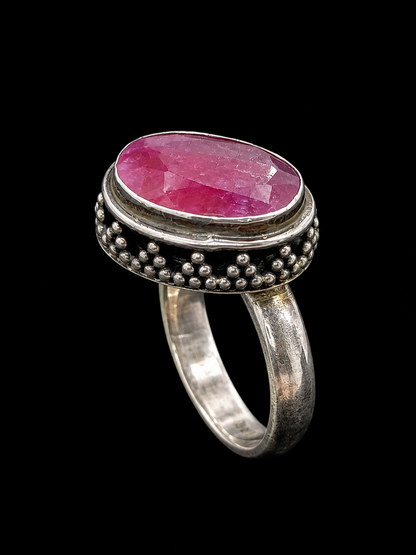 A silver-tone ring with an oval pink CZ stone, set in a textured band.