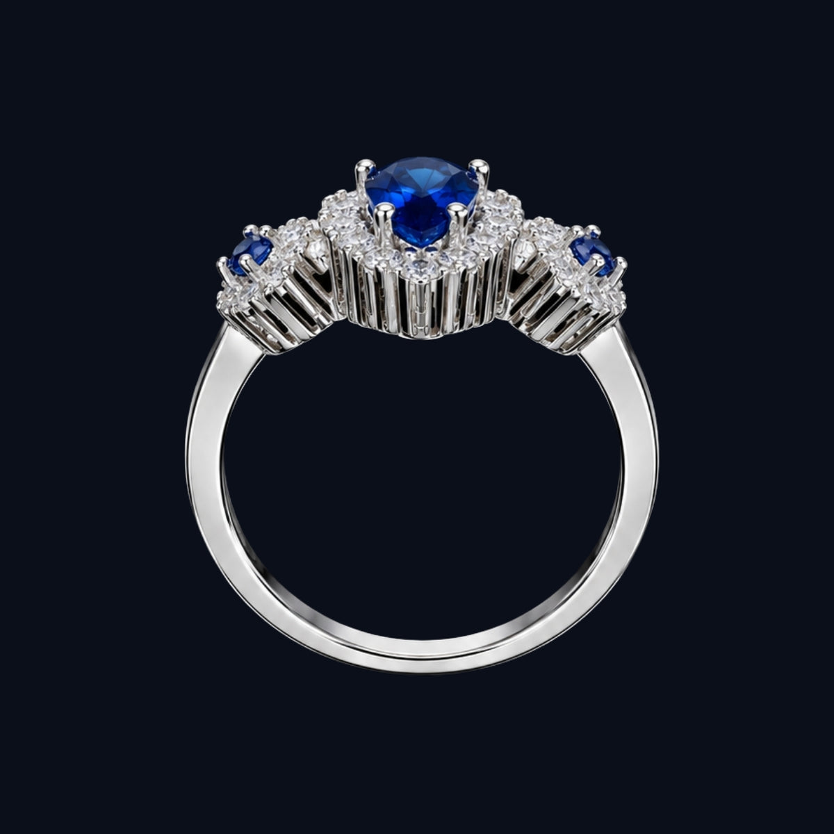 A silver tone ring with a blue CZ stone at its center, surrounded by smaller white CZ stones.