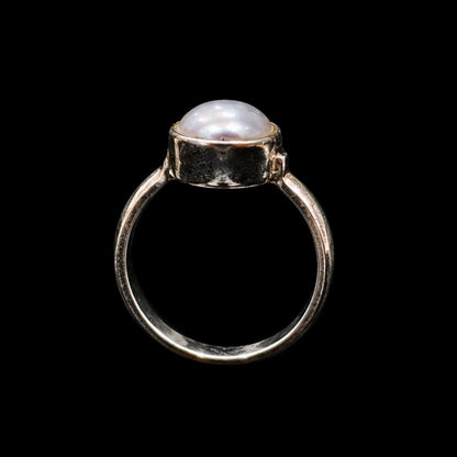 A silver ring with a round pearl on a black background.