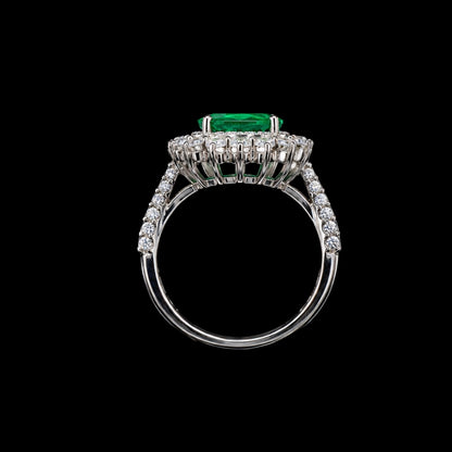 A silver ring with an emerald stone and CZ stones on a black background.