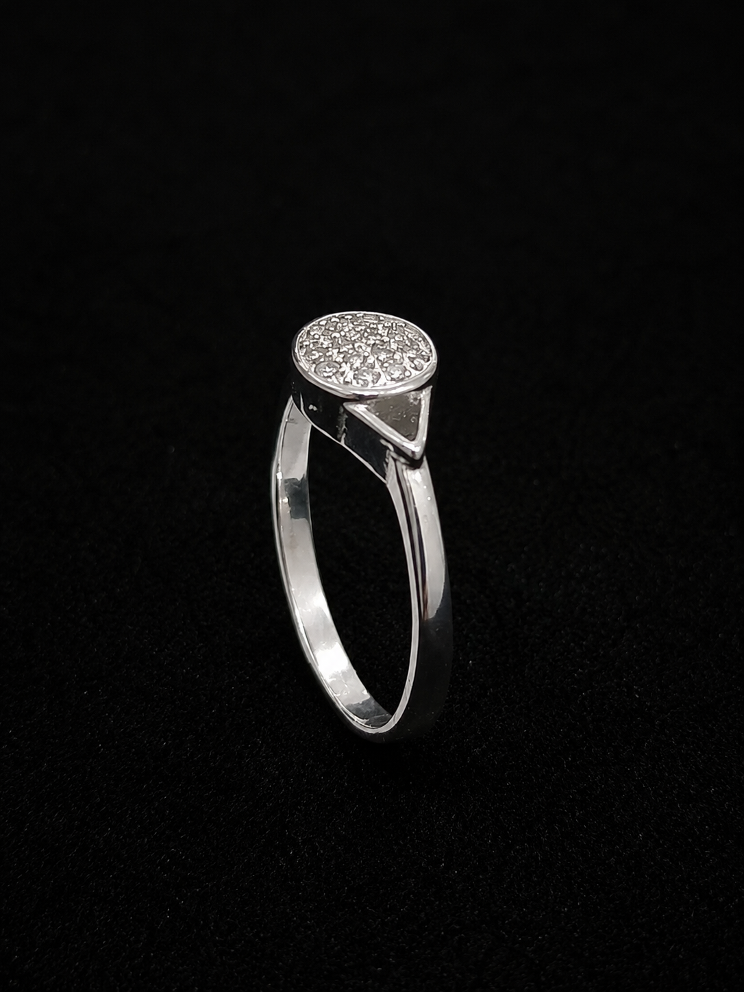 A silver ring with a round CZ stone setting, on a black background.