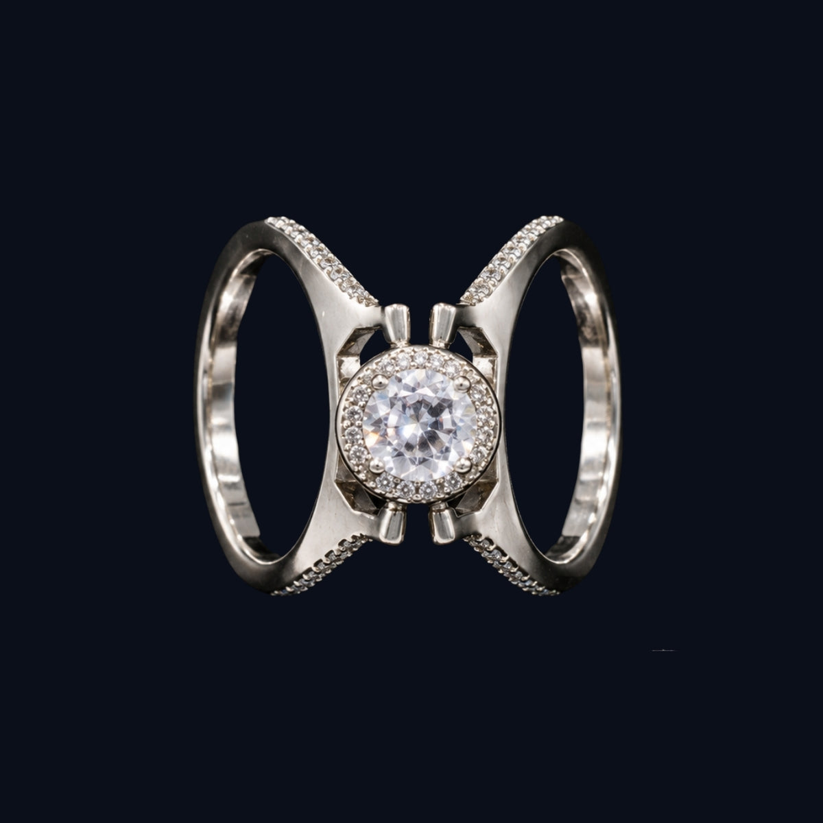 A silver-tone ring with a round-cut CZ stone surrounded by smaller CZ stones, set in a crisscross design.
