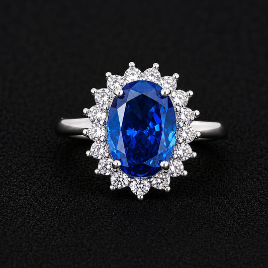A silver-tone ring with a large blue sapphire stone surrounded by smaller clear stones.