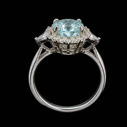 A silver-tone ring with a large blue gemstone and smaller clear gemstones, set in a delicate floral design.