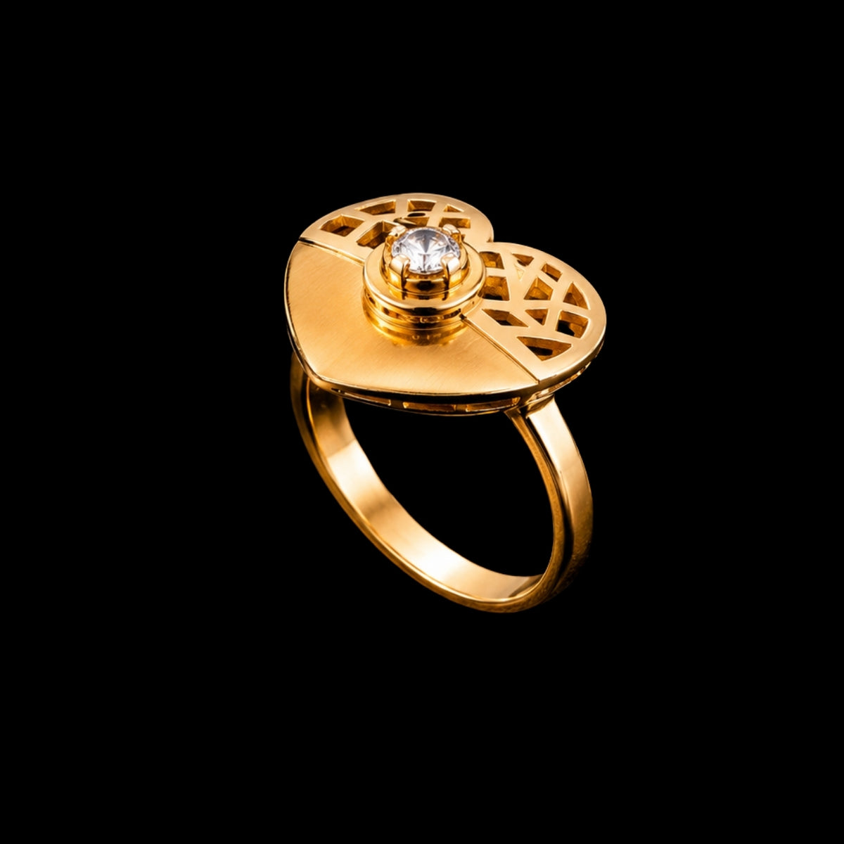 A gold-tone ring with a round CZ stone and a geometric design.