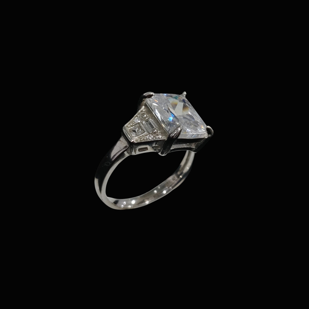 A silver ring with a large, clear cubic zirconia stone and smaller stones set in a modern geometric design.