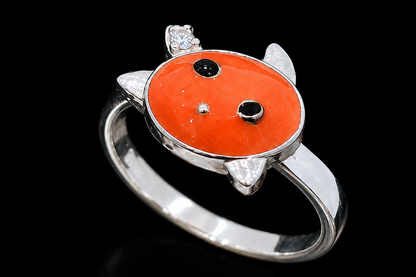 A silver ring with an orange turtle design and black stones