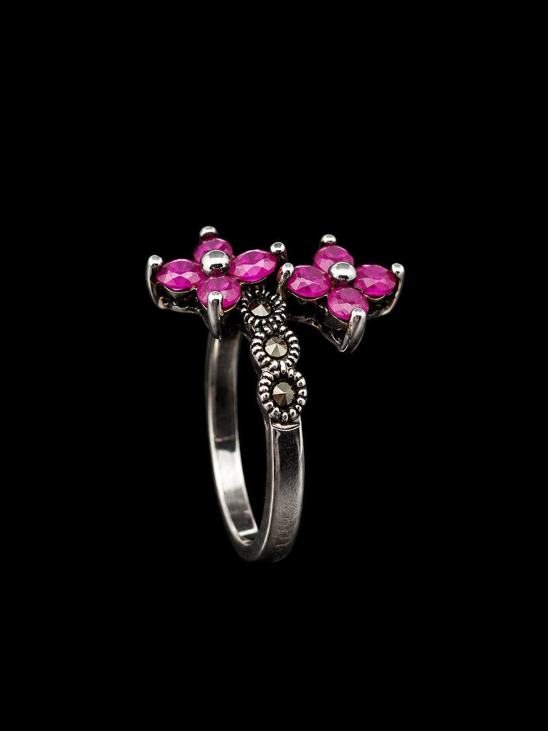 A silver ring with pink CZ stones in a floral design.