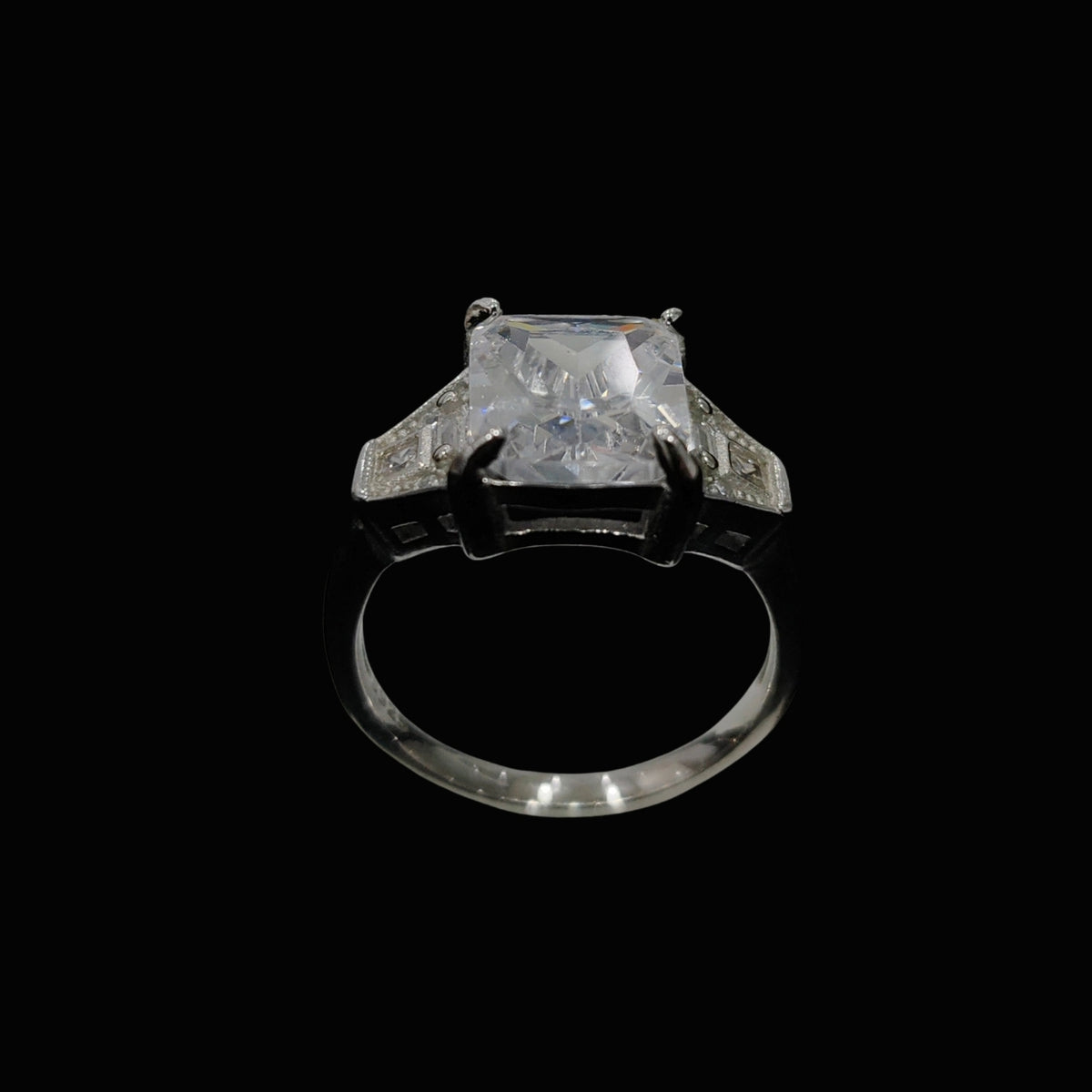 A silver-tone ring with a large clear CZ stone and intricate details.