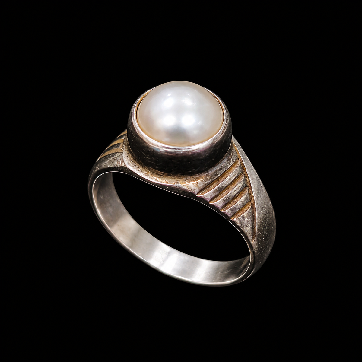 A silver ring with a pearl at its center, set against a neutral background.