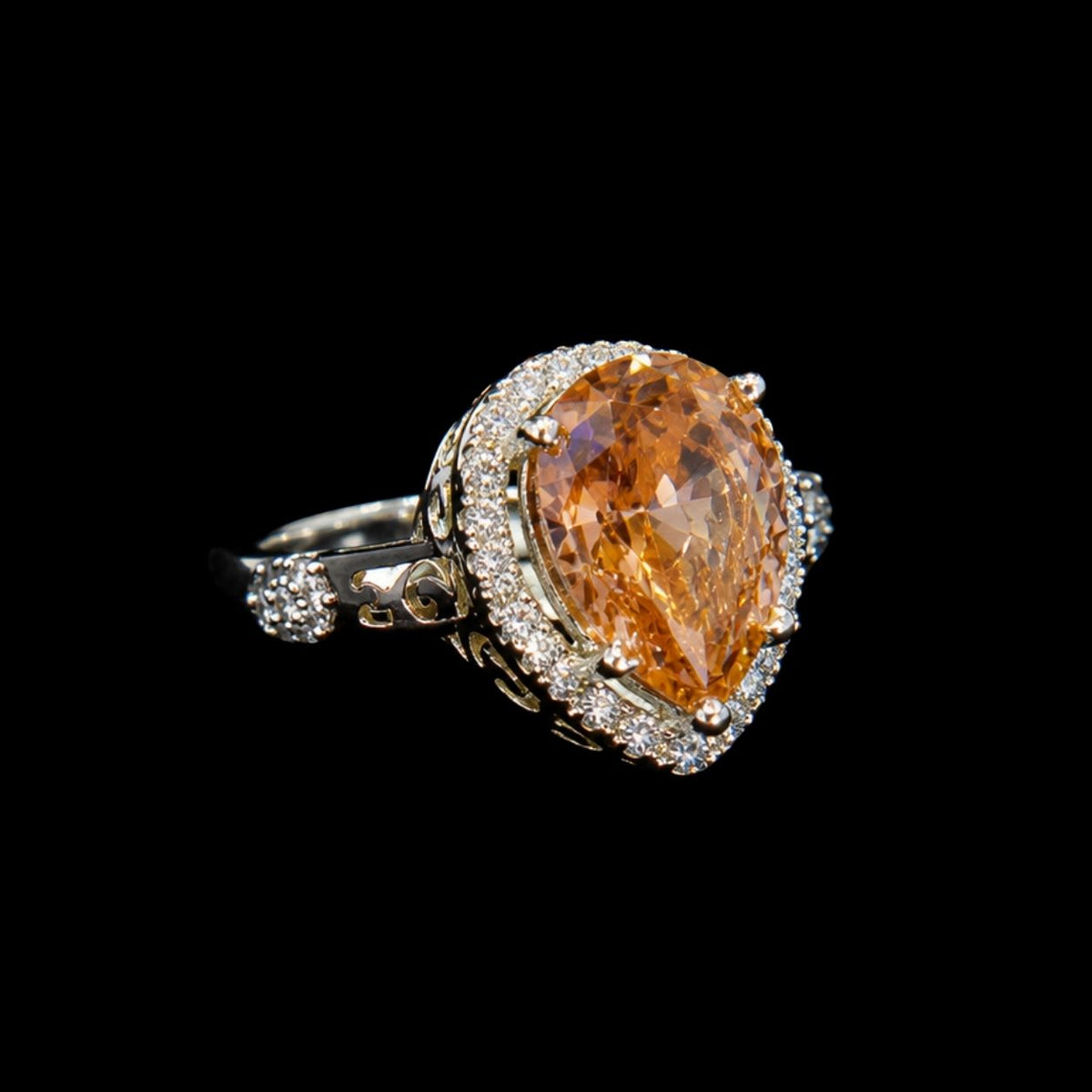A golden teardrop-shaped ring with an ornate design and silver tone.