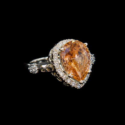 A golden teardrop-shaped ring with an ornate design and silver tone.