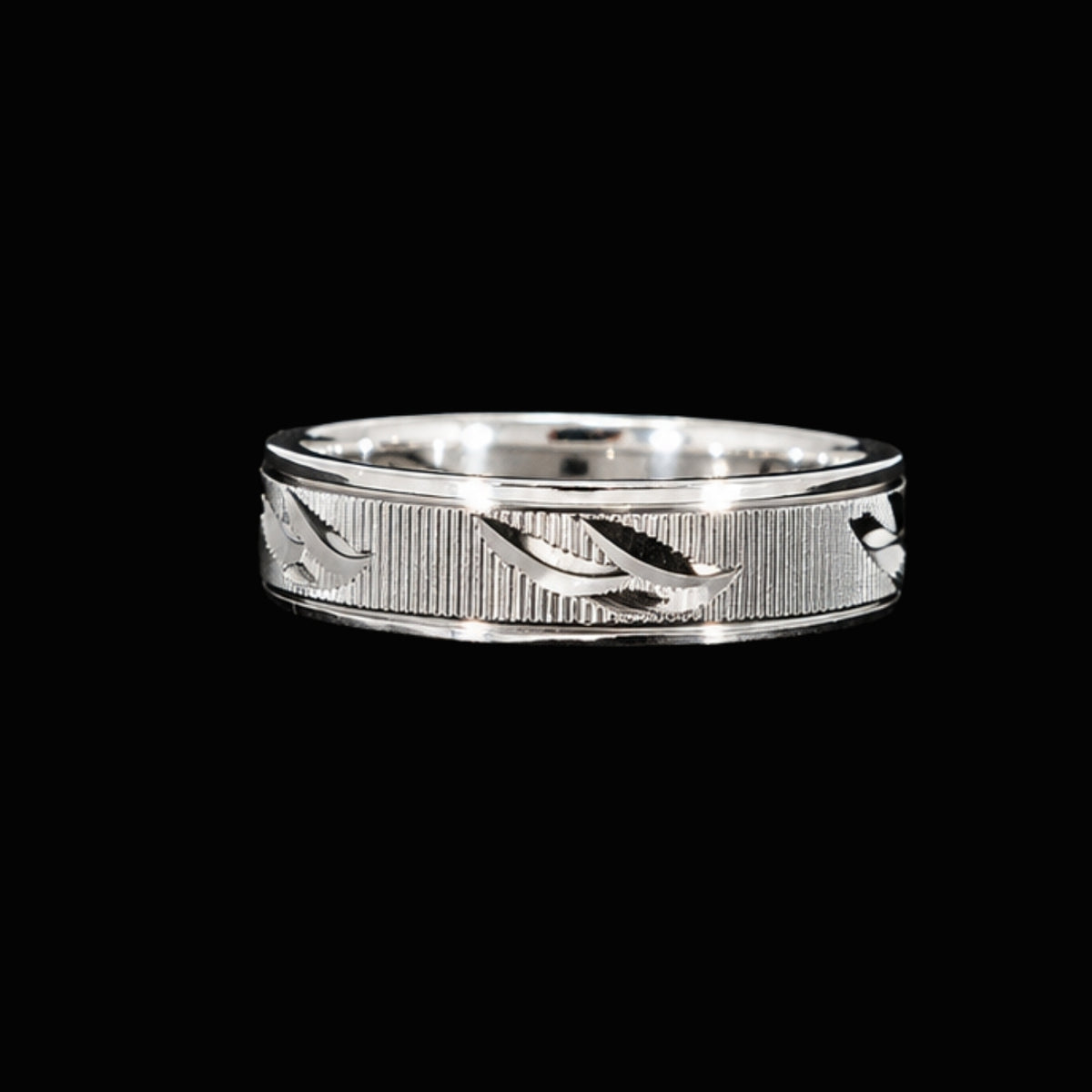 A silver ring with an engraved design, set against a neutral background.