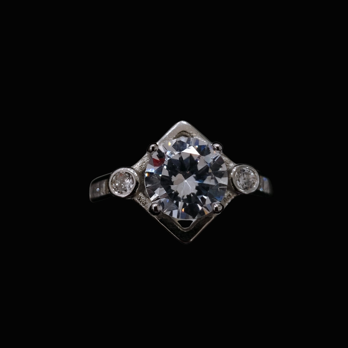 A silver ring with a large clear CZ stone and two smaller stones on either side.
