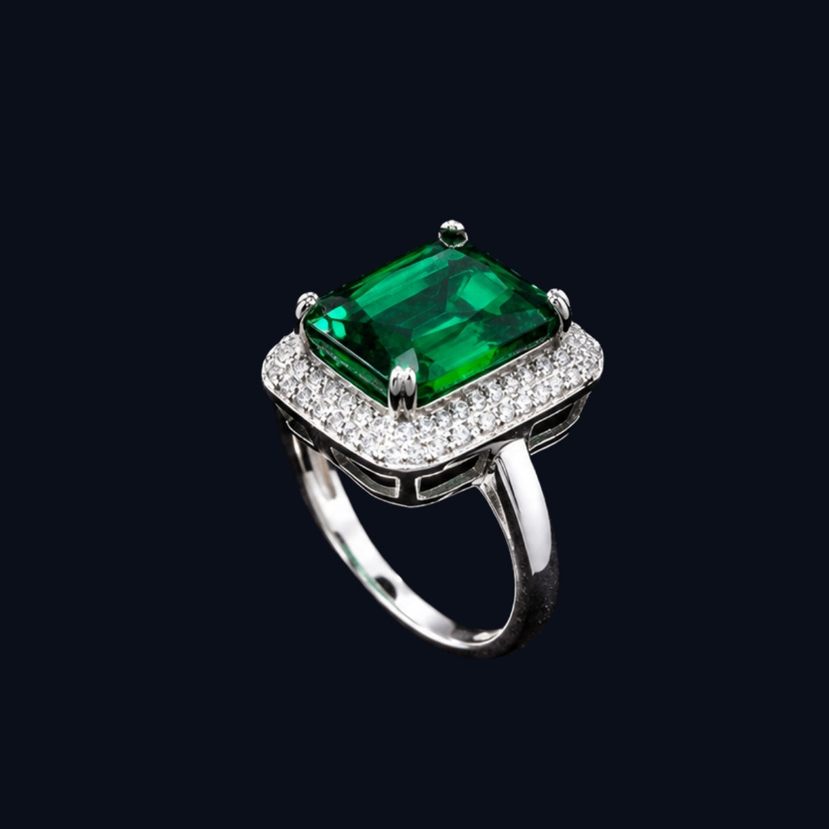 A silver ring with an emerald green CZ stone, set in a geometric design.