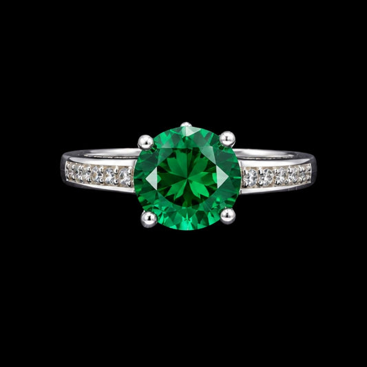 A silver ring with an emerald stone in the center, set against a plain background.