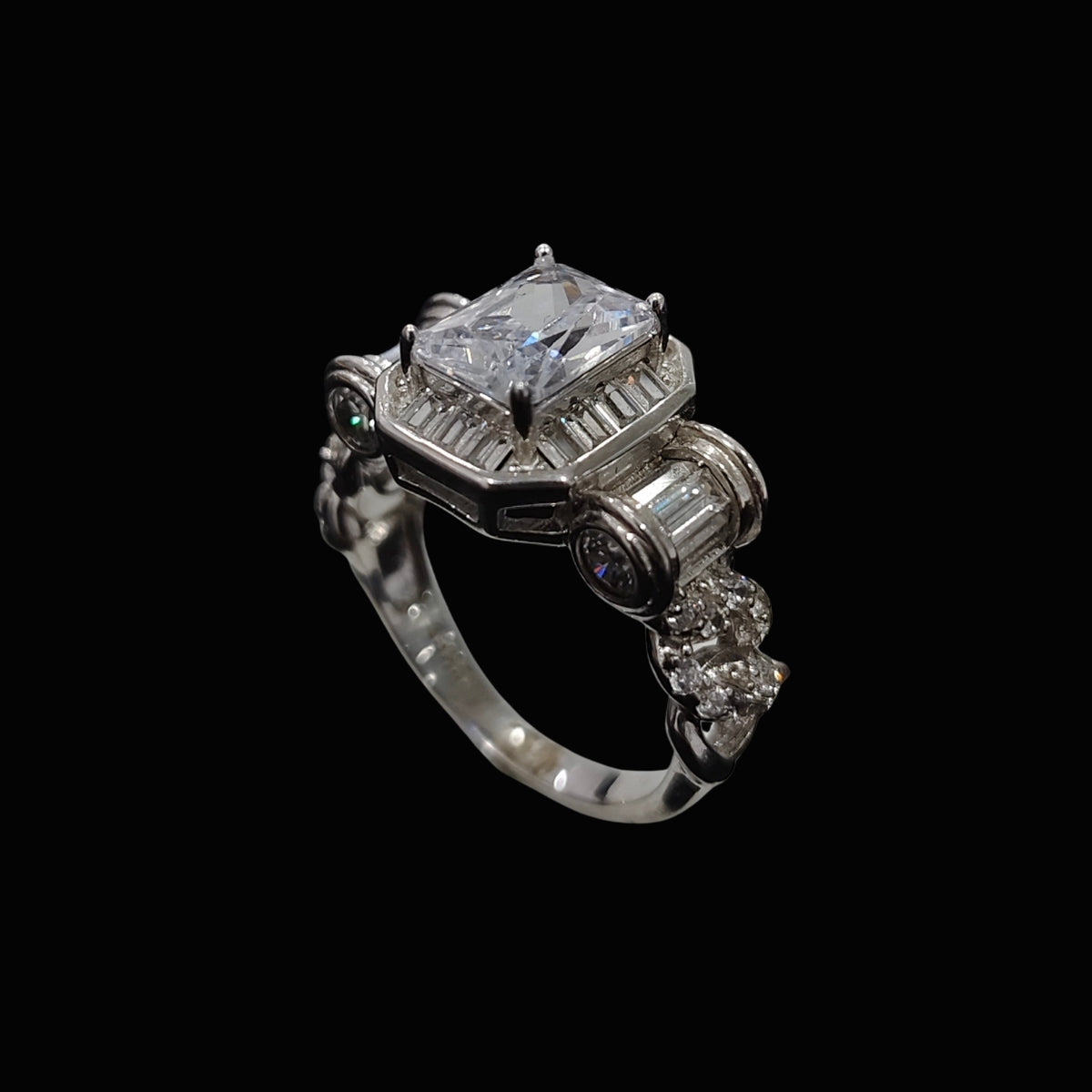 A silver ring with a large clear CZ stone and smaller stones, set against a dark background.