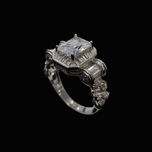 A silver ring with a large clear CZ stone and smaller stones, set against a dark background.