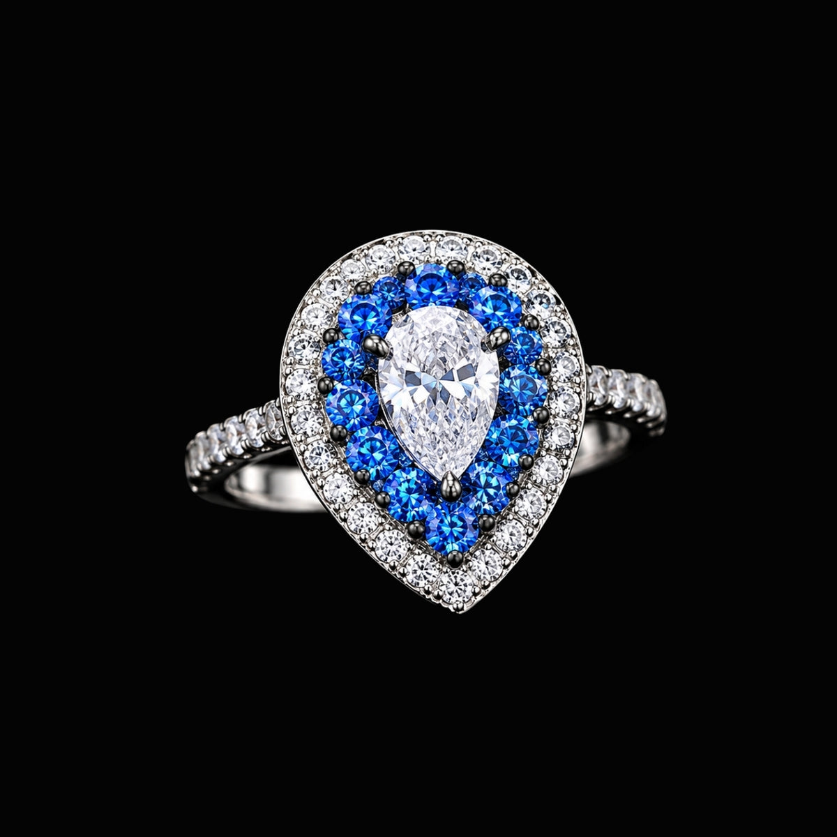 A pear-shaped ring with a large CZ stone and smaller blue CZ stones surrounding it, set in silver tone metal.