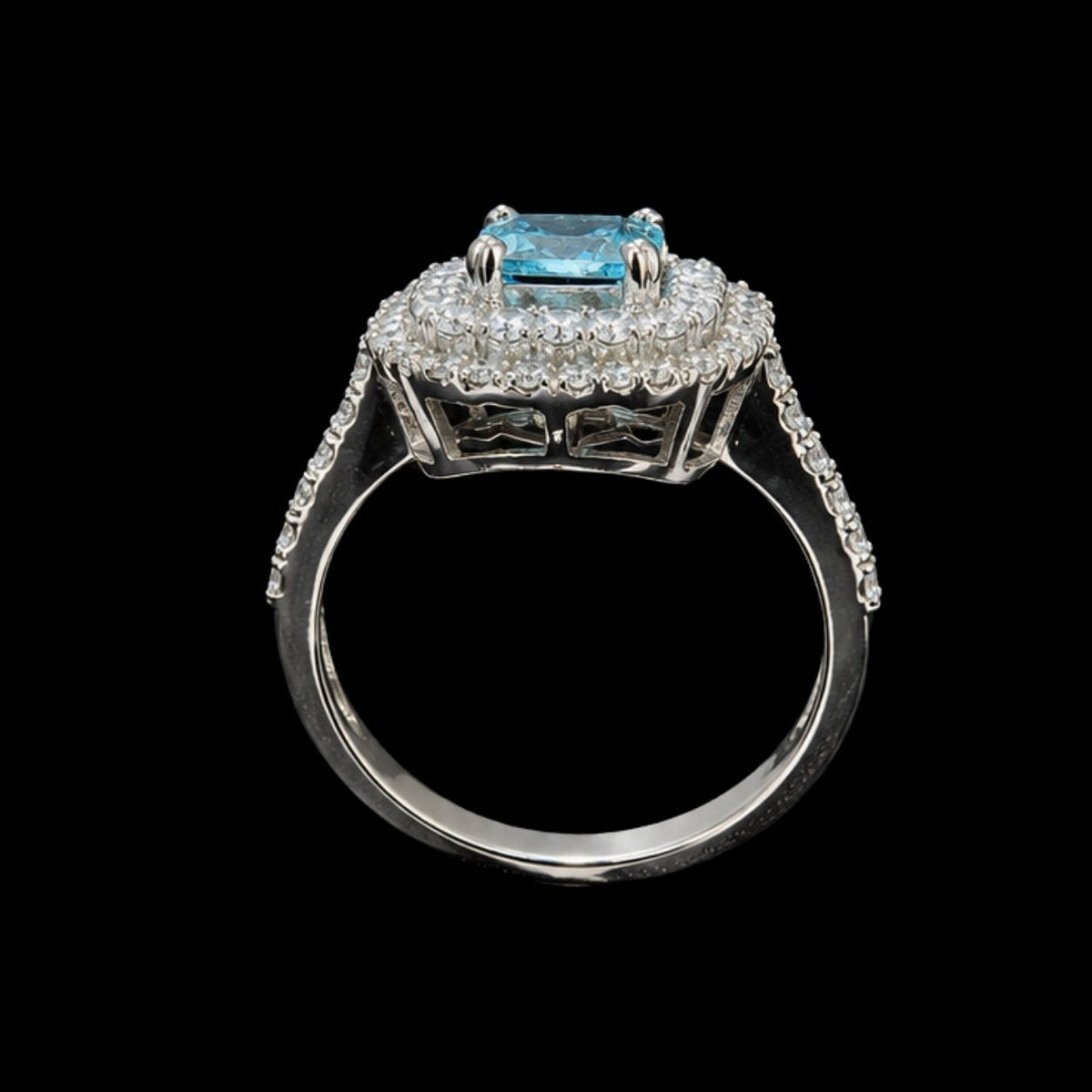 A silver ring with a blue gemstone and clear stones on a black background