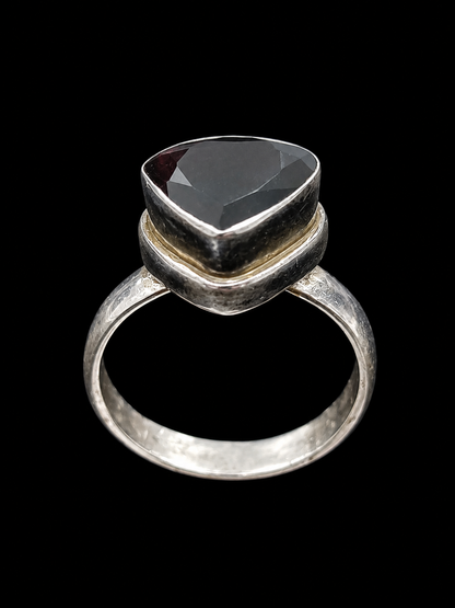 A ring with a large, faceted black gemstone set in a silver-tone setting.