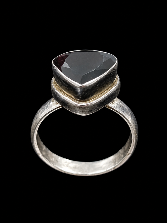 A ring with a large, faceted black gemstone set in a silver-tone setting.