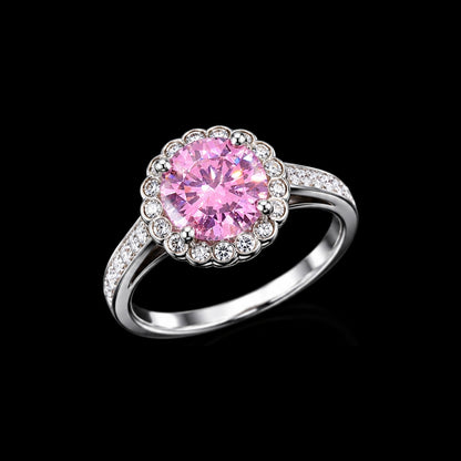 A pink CZ stone surrounded by a halo of smaller stones, set in a silver-tone metal, on a black background.