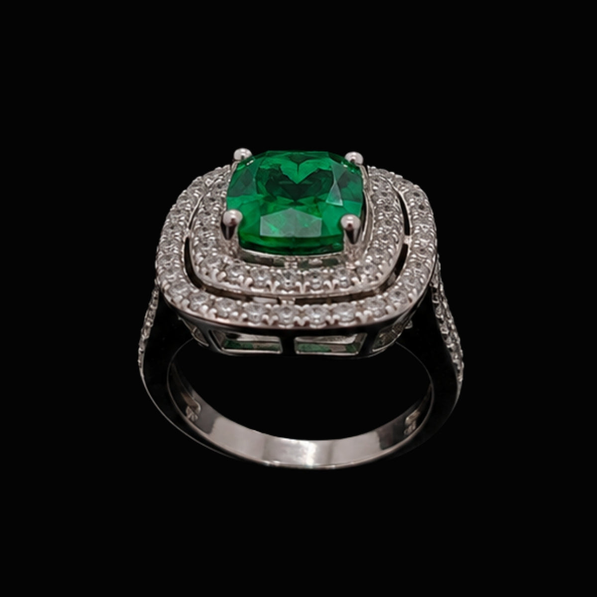 A silver ring with an emerald stone and CZ stones on a black background