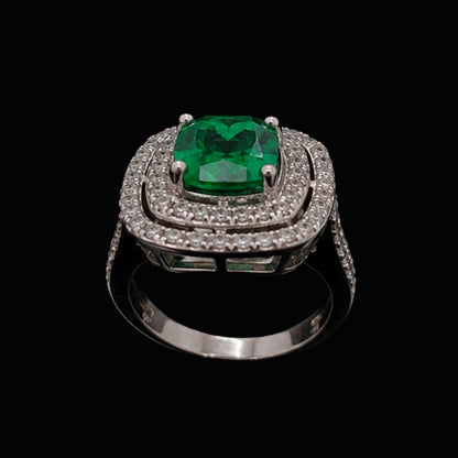 A silver ring with an emerald stone and CZ stones on a black background