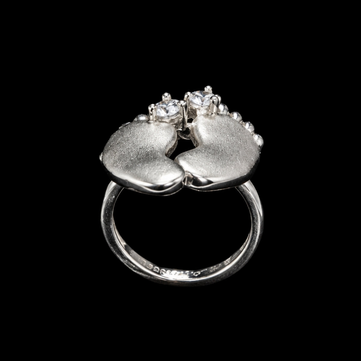 Silver ring with two baby feet in a tender embrace, adorned with sparkling CZ stones.