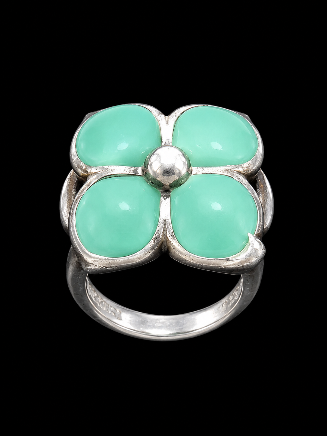 A silver ring with a floral design and mint green stones.